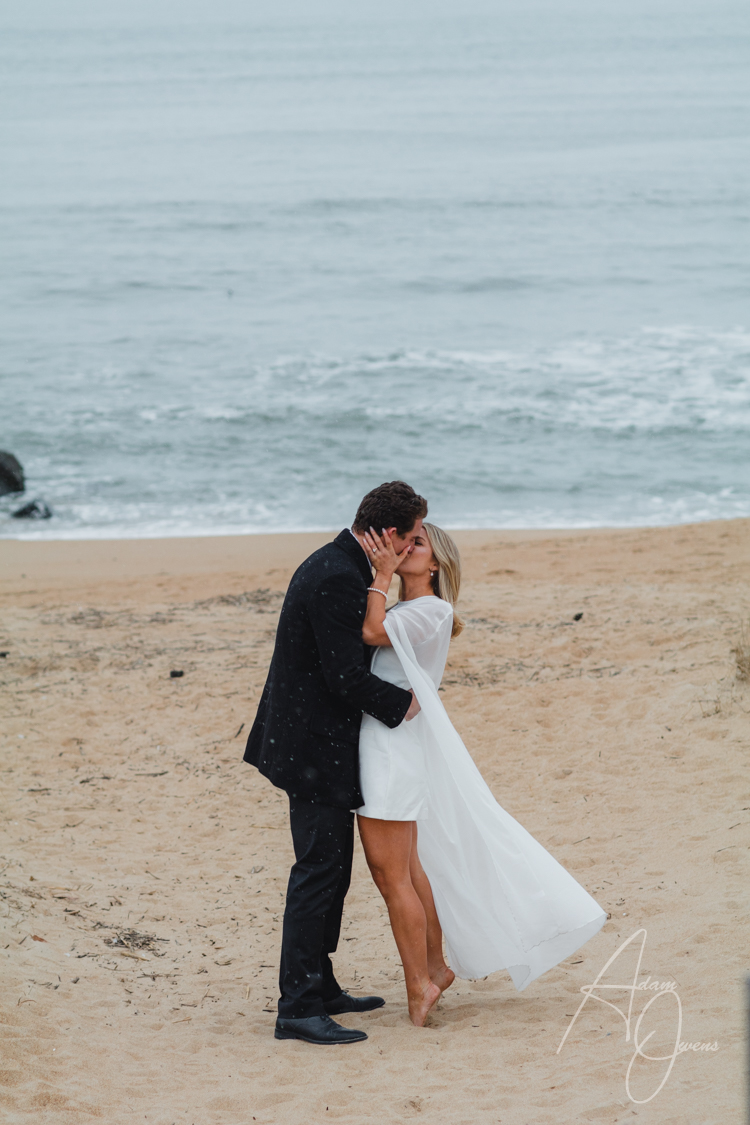 A husband and wife kiss on the beach